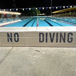 Custom pool safety message tile with durable kiln-fired ceramic finish in a residential pool.